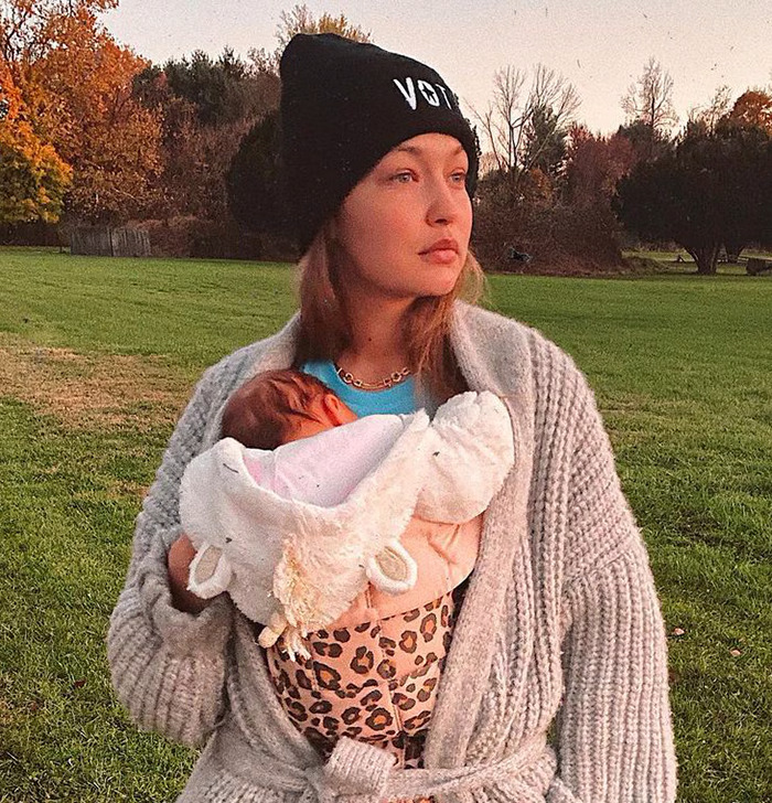 Gigi Hadid holding her daughter Khai in a cozy outdoor setting, both in warm clothing.