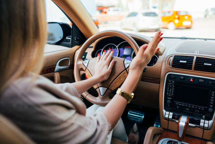 A woman driving a car, focusing on the dashboard and rearview, symbolizing memorable words from her father.