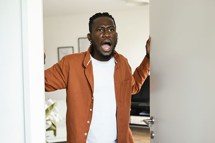 A surprised person in a doorway wearing an orange shirt and white t-shirt, reacting to a woman's unexpected move out. A surprised person in a doorway wearing an orange shirt and white t-shirt, reacting to a woman's unexpected move out.