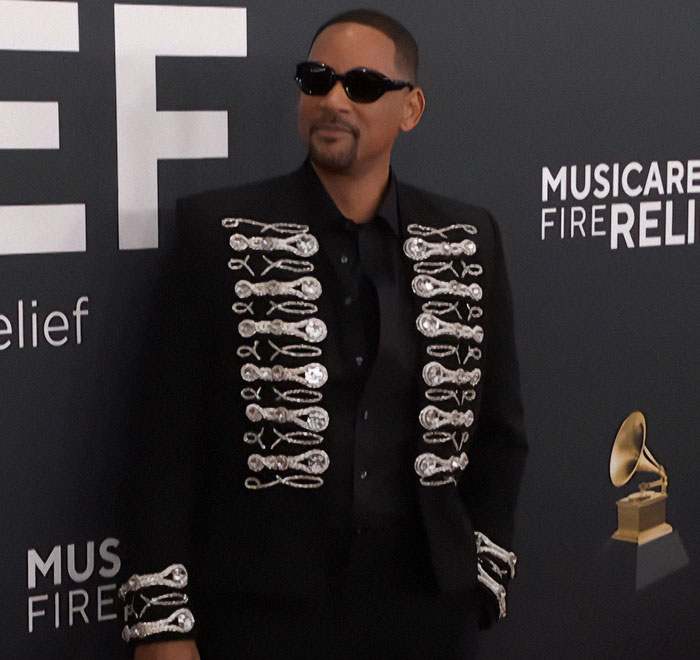 Man in a stylish black outfit with detailed embroidery at a music event, focusing on Grammys comeback. Man in a stylish black outfit with detailed embroidery at a music event, focusing on Grammys comeback.