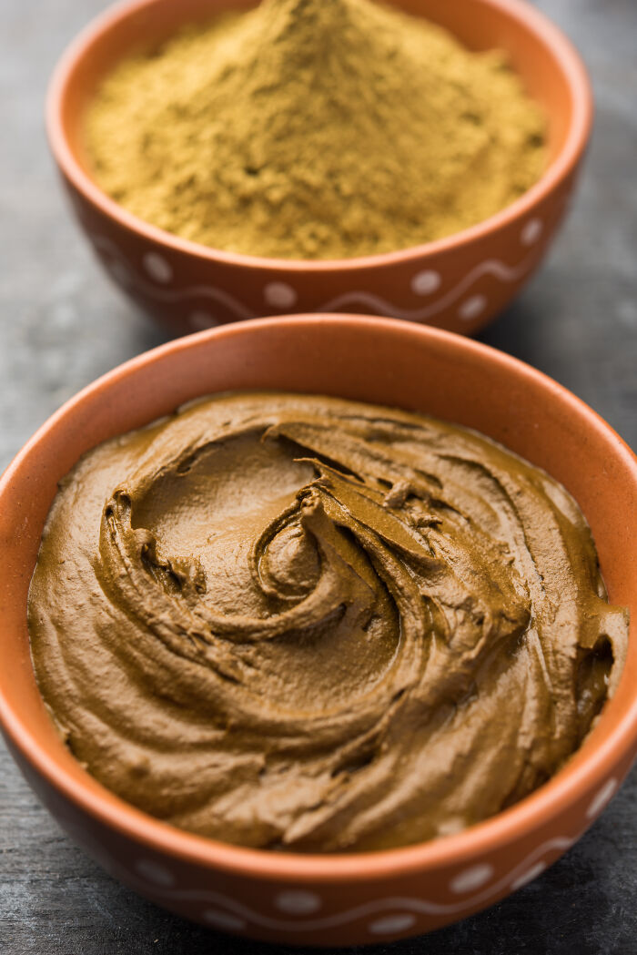 Two ceramic bowls with overlooked ingredients: a creamy paste and a mound of powdered spice.