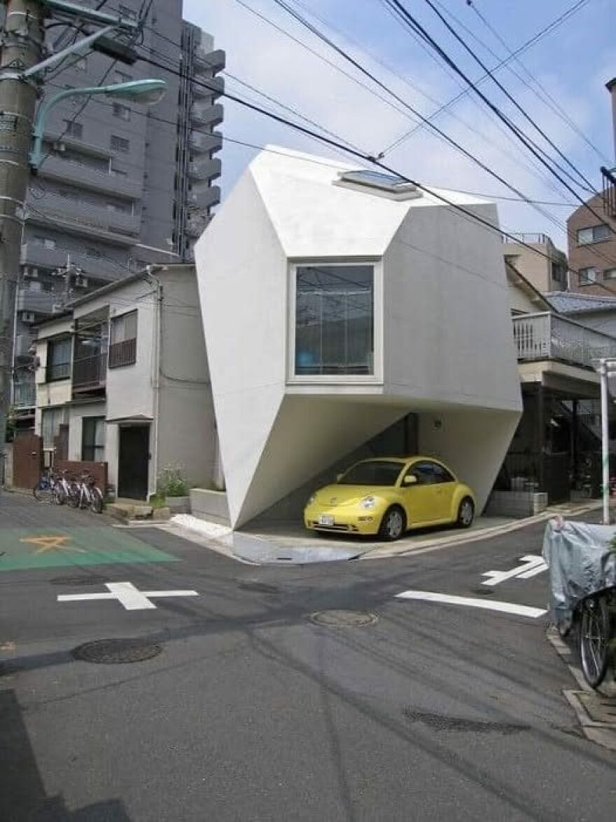 Unusual architecture: a building with a geometric design and a yellow car parked underneath.