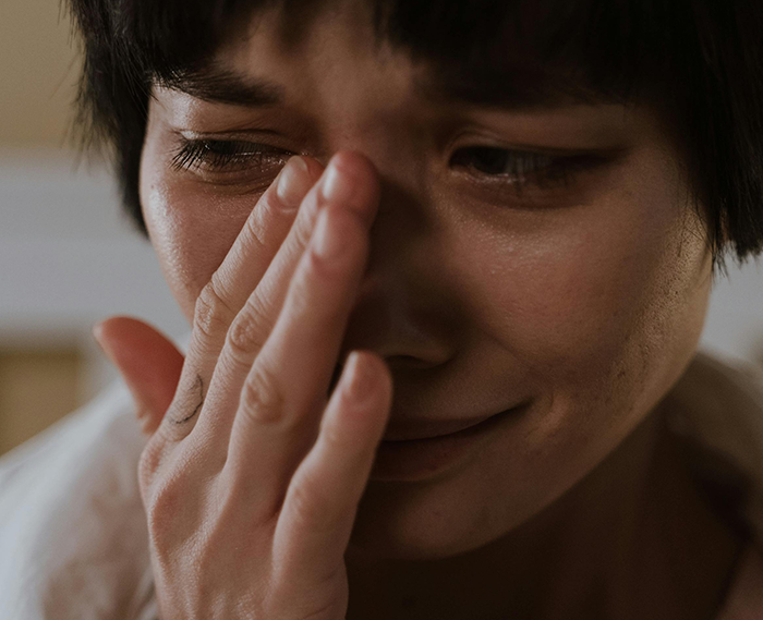 A woman looking upset, covering her face with her hand, highlighting the challenges in a marital space-sharing issue.