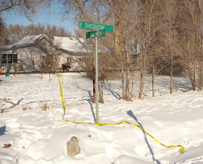 Snow-covered crime scene near house with street signs at East Shoshone and South Big Horn.