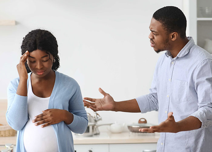 Man arguing with his pregnant wife in a kitchen setting.