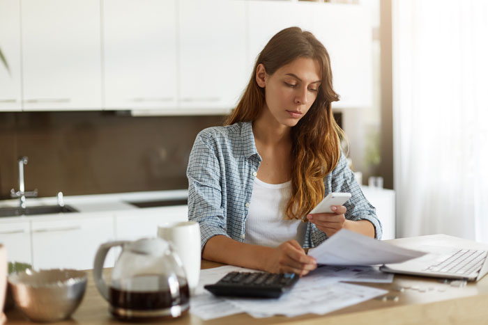 Woman at a table with smartphone, stressed about a job-hopper's future and family decisions.