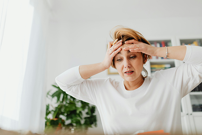 A worried woman holding her head, reflecting on hubby's journal, wearing a white shirt in a bright room. A worried woman holding her head, reflecting on hubby's journal, wearing a white shirt in a bright room.