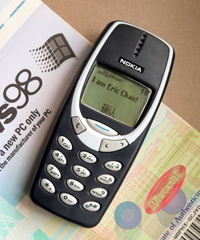 A durable Nokia phone displaying a message, placed on vintage software packaging, highlighting design longevity.