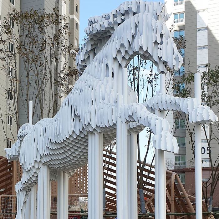 Metal pipe sculpture of a rearing horse by Yi Chul Hee, displayed outdoors in an urban setting.