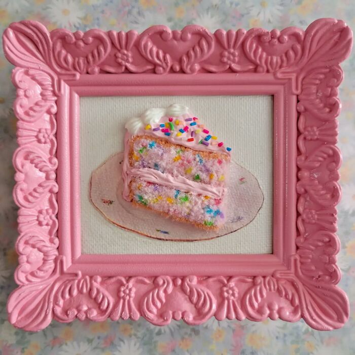 Hyper-realistic embroidered cake slice in a pink ornate frame.