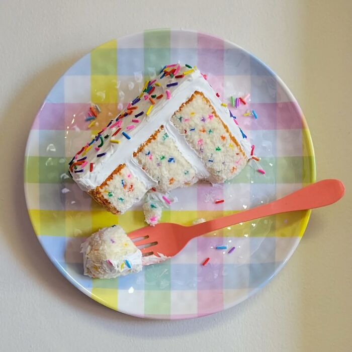Hyper-realistic embroidered dessert resembling a slice of funfetti cake on a plaid plate with a pink fork.