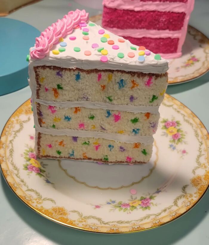 Hyper-realistic embroidered cake slice with colorful details on a floral plate.