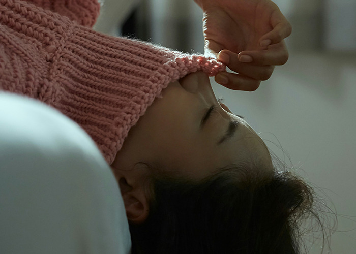 Person covering face with sweater sleeve, illustrating one of the must-have life skills that nobody taught these internet users.