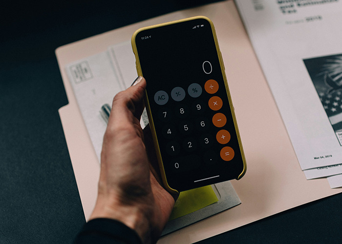 Hand holding a smartphone with calculator app open, representing essential life skills nobody taught these internet users.
