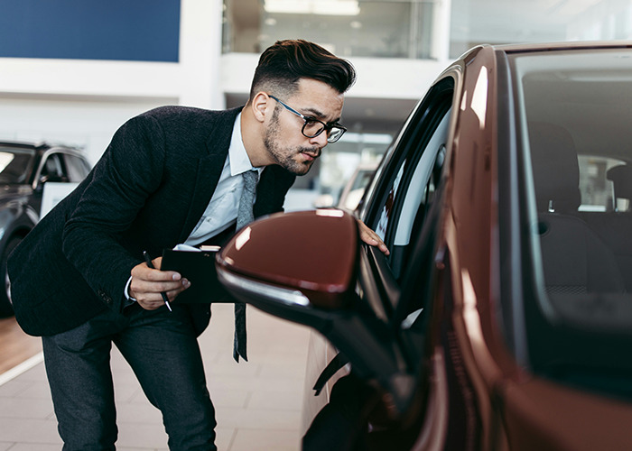 Man inspecting a car at a dealership, demonstrating essential life skills.
