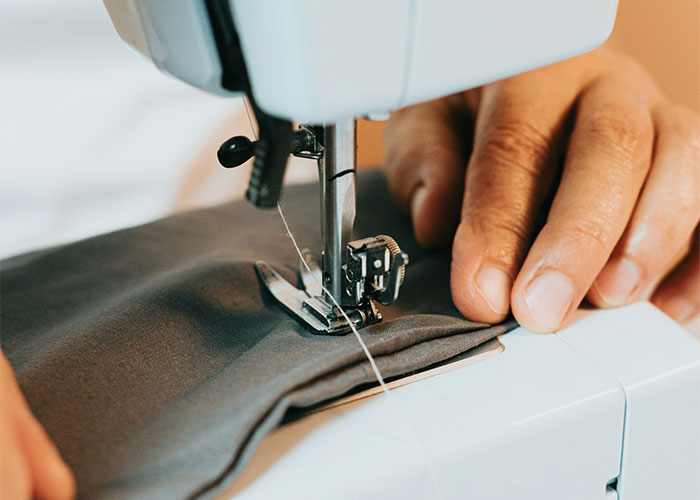 Close-up of hands sewing fabric with a machine, illustrating must-have life skills for practical everyday use.