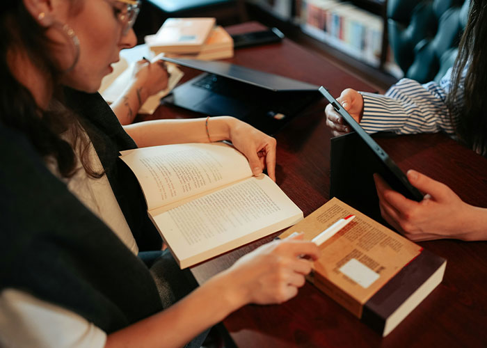 Two people studying together with books and a tablet, focusing on must-have life skills for internet users.