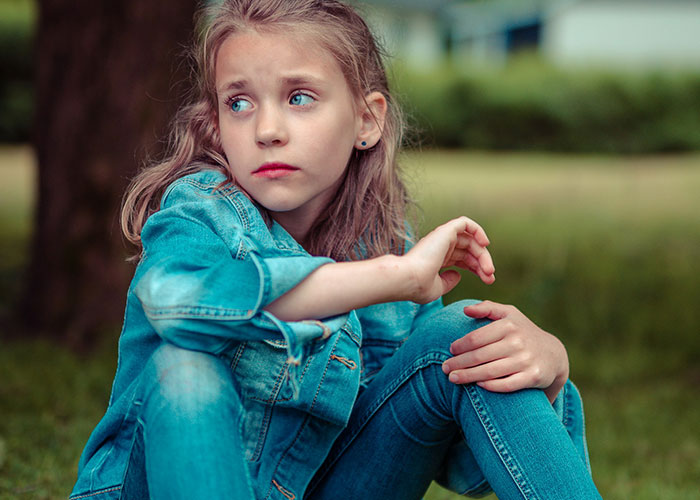 Young girl sitting outdoors looking thoughtful, representing must-have life skills for internet users today.