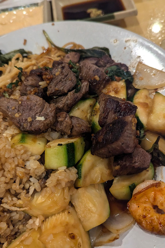 Close-up of a stir-fry dish possibly illustrating food scams, showing beef, rice, zucchini, and onion.