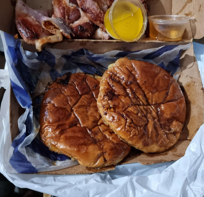 Two stale buns in a takeout box with minimal filling, illustrating food scams.
