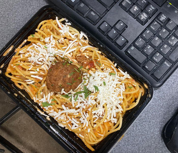 Plastic tray of spaghetti with one meatball, highlighting food scams.