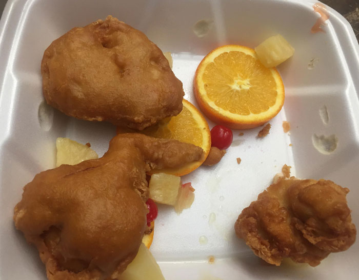 Unappetizing takeout meal with fruit garnishes, illustrating food scams with disappointing portions.