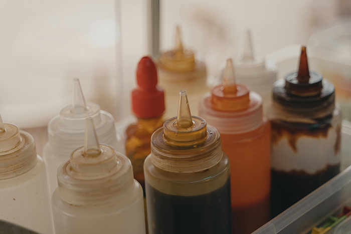 Various sauce bottles arranged together in a tray, showcasing different colors and types for children's meals.