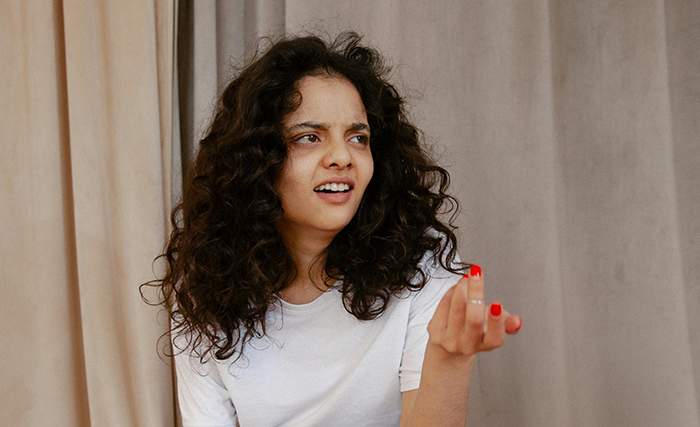 A woman wearing a white shirt appears upset, gesturing with her hand, possibly due to sauce in children's meals.