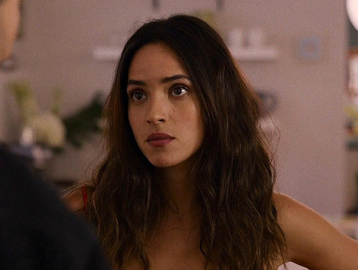 Young woman with long hair, indoors, associated with Jason Momoa on red carpet.