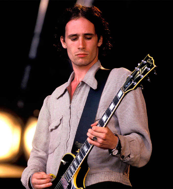 Musician playing guitar on stage, representing tragically passed celebrities.