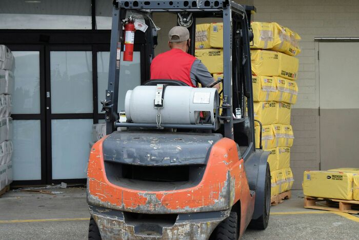 Person operating a forklift, highlighting assumptions about jobs, near stacks of packaged goods.