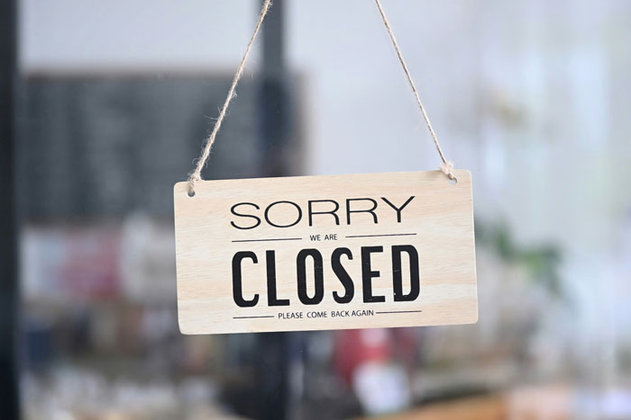 Closed sign hanging on a door, related to Joann fabric and craft retailer store closures announcement.