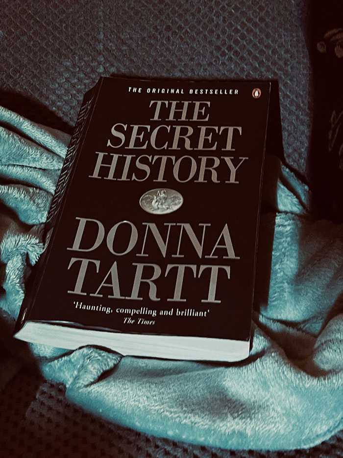 "The Secret History book on a cozy blanket, inviting readers to explore its intriguing book quotes."