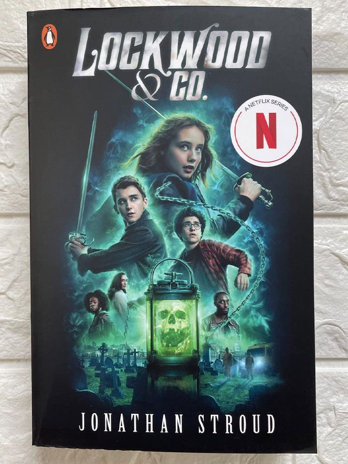 "Book cover of 'Lockwood & Co.' by Jonathan Stroud, showcasing characters and a glowing skull lantern."