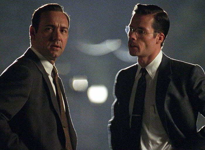 Guy Pearce and Kevin Spacey in suits having a conversation outdoors at night.