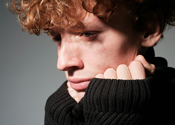 Young person looking sad, wearing a black sweater, reflecting the topic of family and LGBTQ+ acceptance.