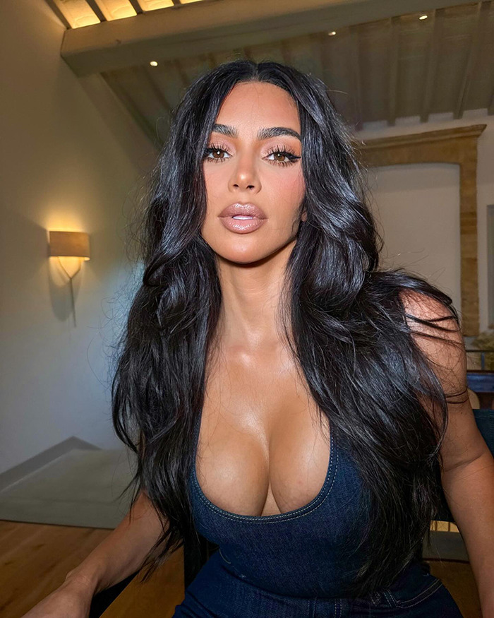 Kim Kardashian with long dark hair wearing a low-cut outfit, posing indoors with soft lighting. Kim Kardashian with long dark hair wearing a low-cut outfit, posing indoors with soft lighting.