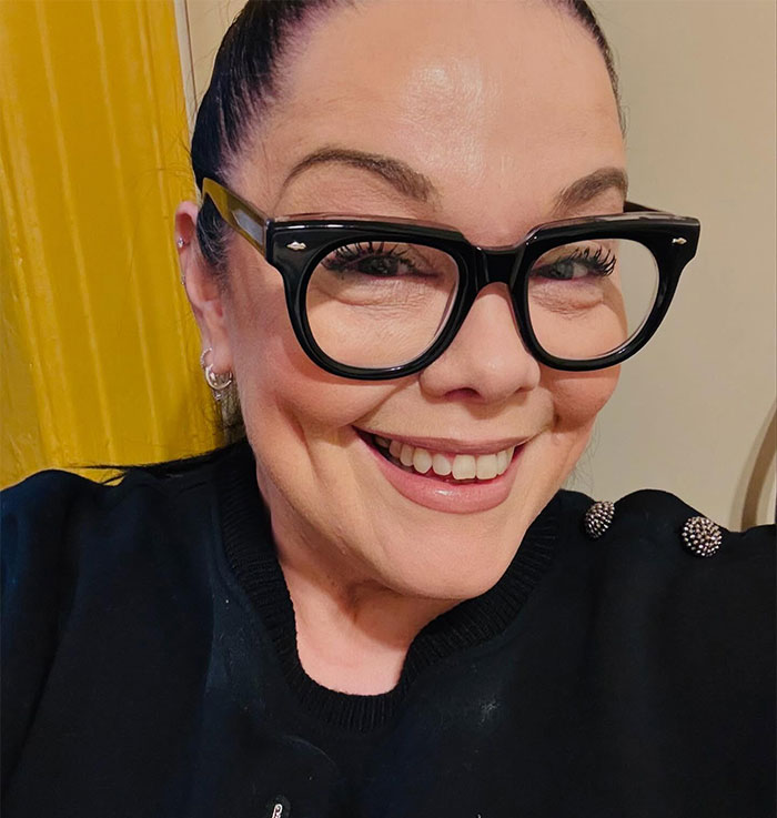 A person smiling, wearing large black glasses, related to celebrity criticism of Bianca Censori's Grammys dress. A person smiling, wearing large black glasses, related to celebrity criticism of Bianca Censori's Grammys dress.