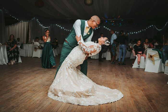 Couple dancing at a wedding reception, with wedding guests in the background.