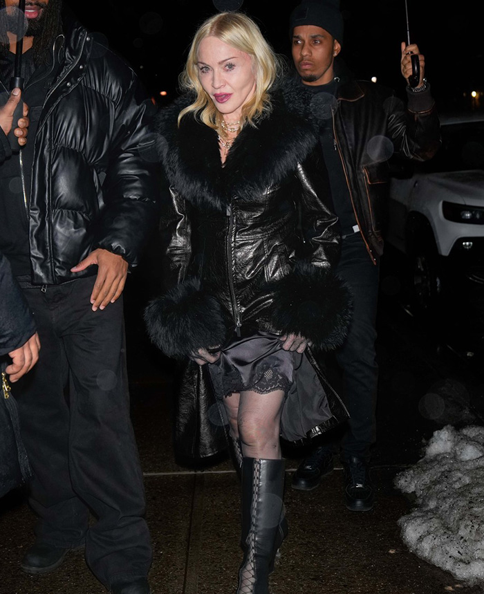 Madonna in NYC, wearing a black fur coat and boots, walking with two people at night.