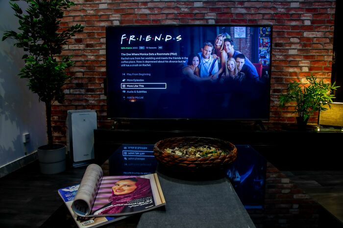 Cozy home setup with TV showing Friends series, highlighting best perks of not having to go to the office advantages.