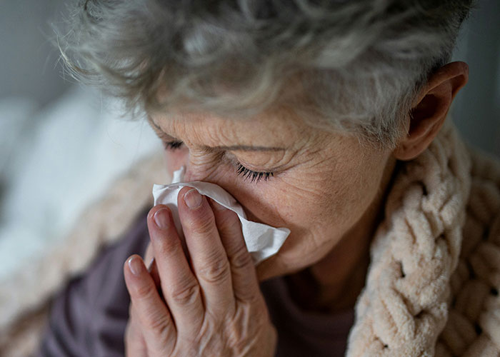 Elderly woman crying, covering face, upset over son's girlfriend's house rule.
