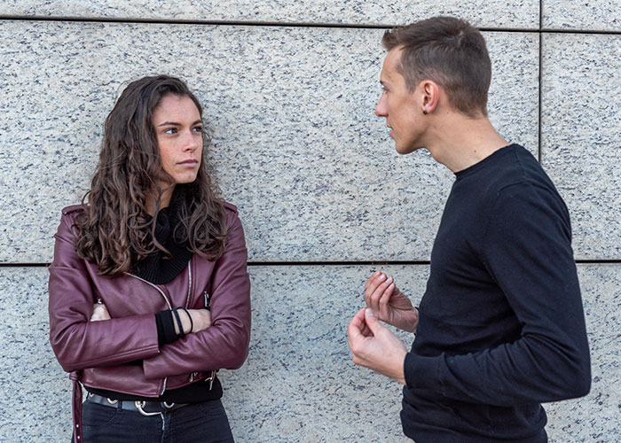Woman looking shocked at coworker's audacity, standing in front of a stone wall. Woman looking shocked at coworker's audacity, standing in front of a stone wall.