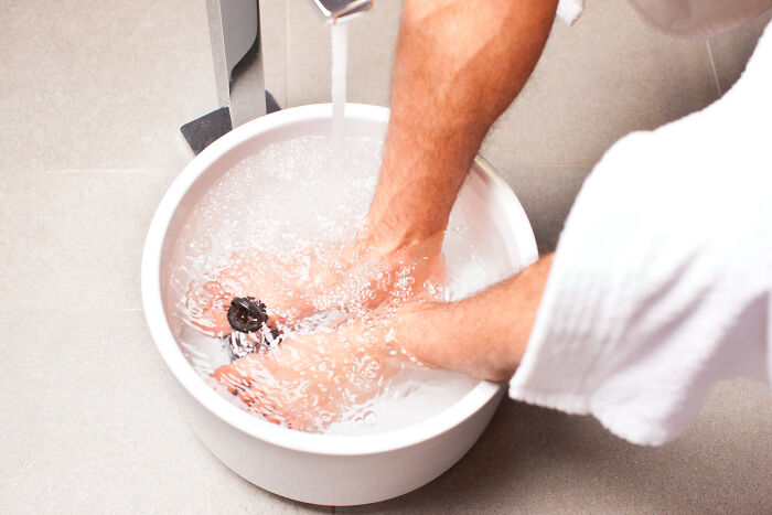 A person cleansing feet in a bowl of water, demonstrating common hygiene habits.