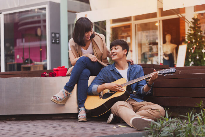 Couple enjoying music together, man playing guitar, as a simple and meaningful Valentine's gift idea.