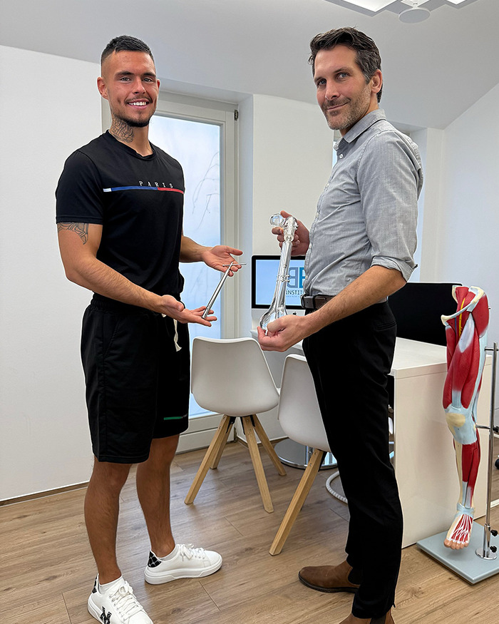 Leon Otremba holding medical devices in a clinic, discussing leg lengthening procedures. Leon Otremba holding medical devices in a clinic, discussing leg lengthening procedures.