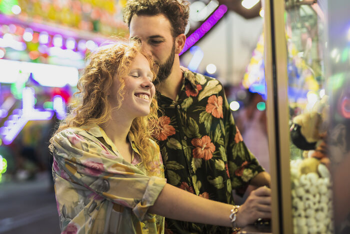 Couple enjoying a fair, a simple and meaningful Valentine's gift idea, surrounded by colorful lights.