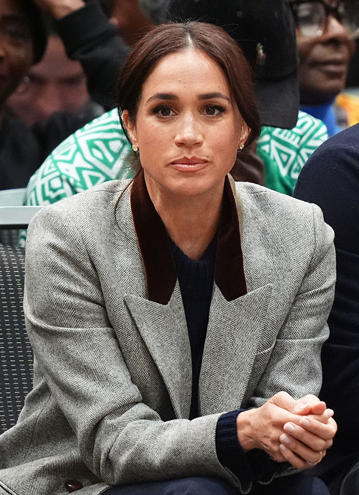 Meghan Markle in a grey blazer seated.