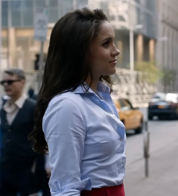 Person in blue shirt on a city street with blurred taxis in the background.