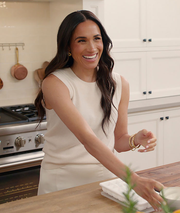 Woman in a kitchen smiling, wearing a sleeveless top, with hair down. Woman in a kitchen smiling, wearing a sleeveless top, with hair down.